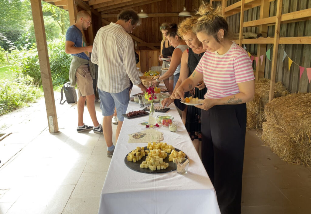Hofführung & Verkostung 1 Erwachsene, die sich etwas zu Essen an einem gedeckten Tisch nehmen